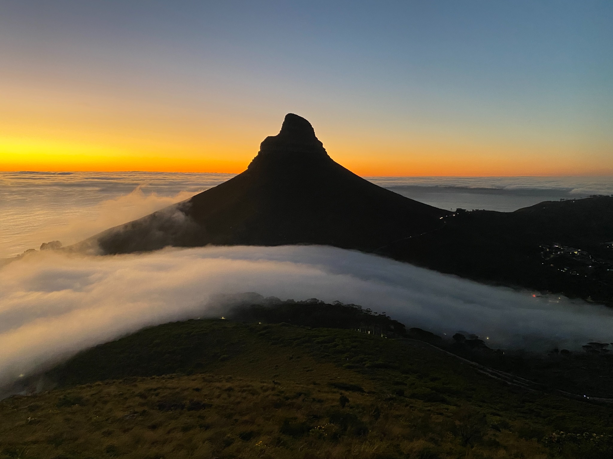 Lion's Head silhouetted above low cloud during golden sunrise light in Cape Town